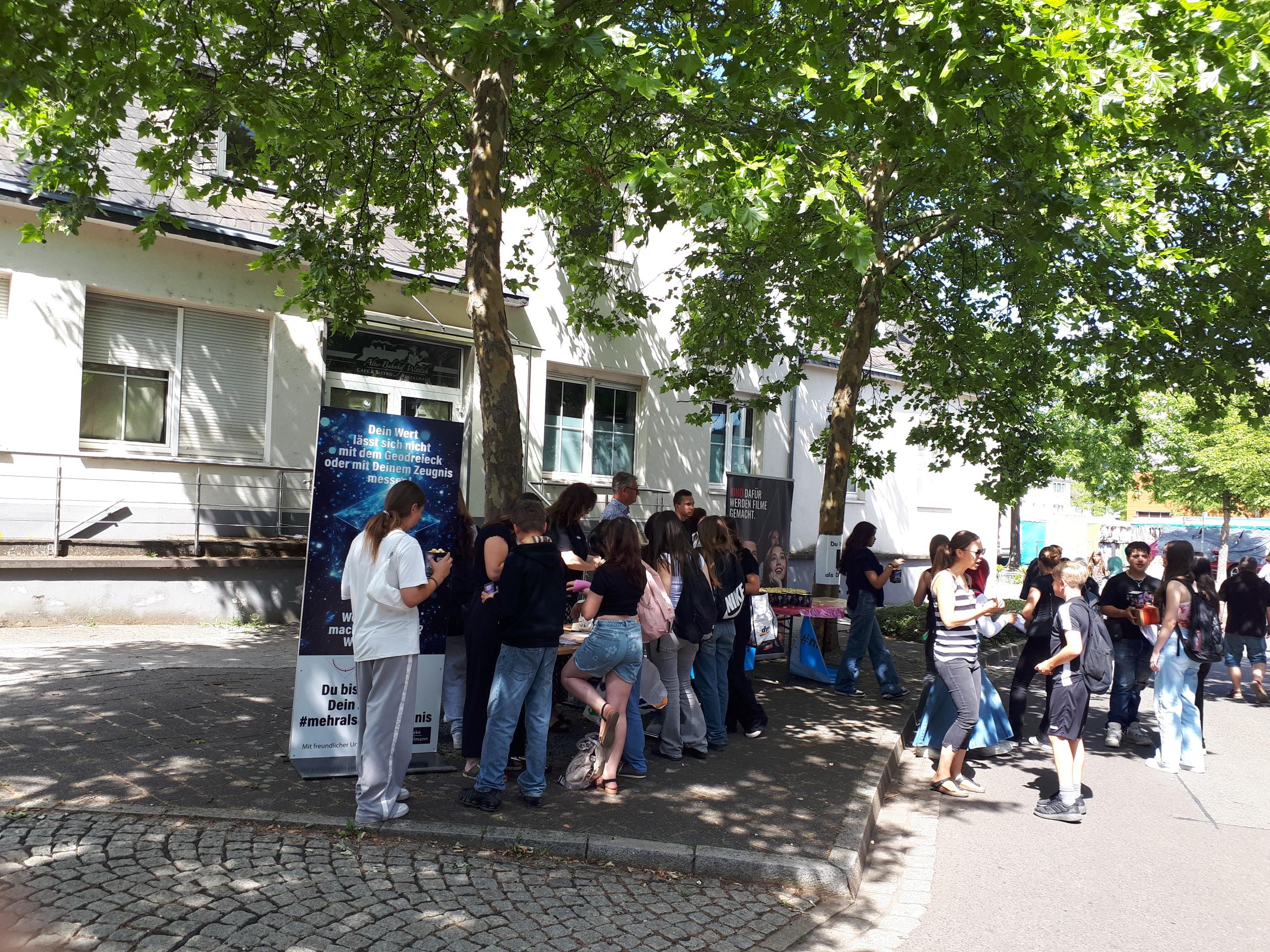 Aktion Letzter Schultag 2025: viele Schüler:innen vor Gebäude unter Bäumen