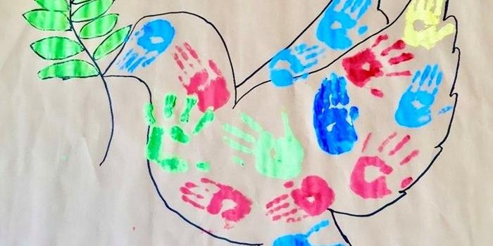 Taube mit Zweig und bunten Handabdrücken