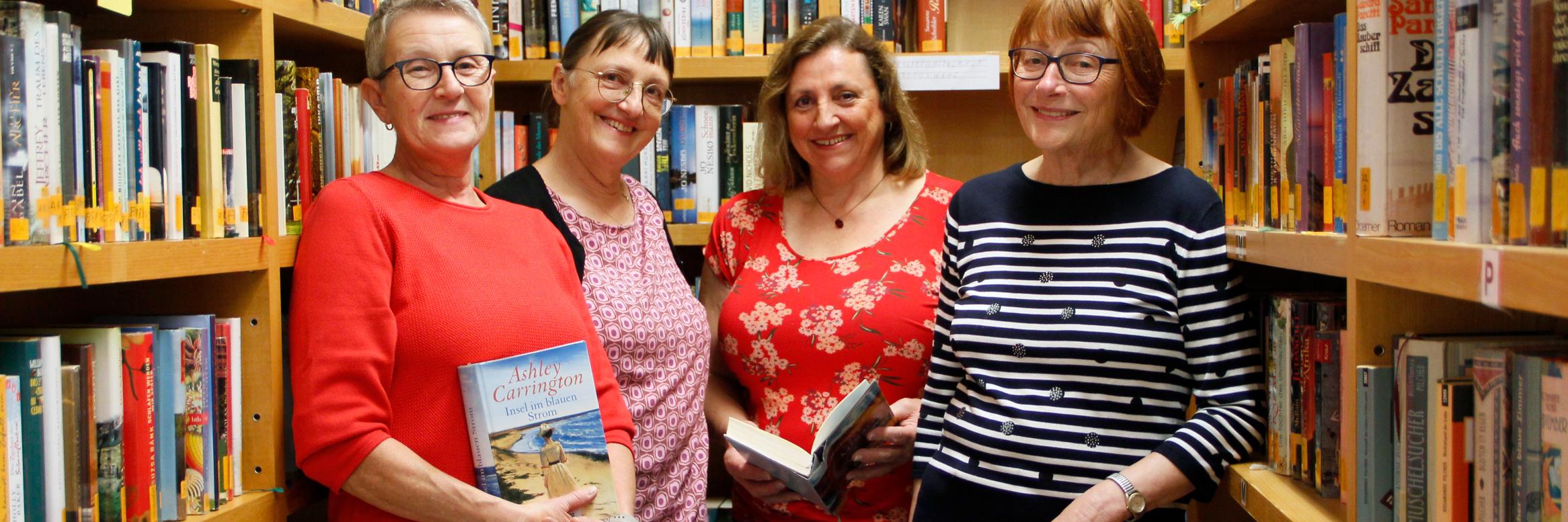 Vier lächelnde, etwas ältere Damen stehen vor Bücherwänden, zwei haben Bücher in der Hand. (c) sb Vier lächelnde, etwas ältere Damen stehen vor Bücherwänden, zwei haben Bücher in der Hand.