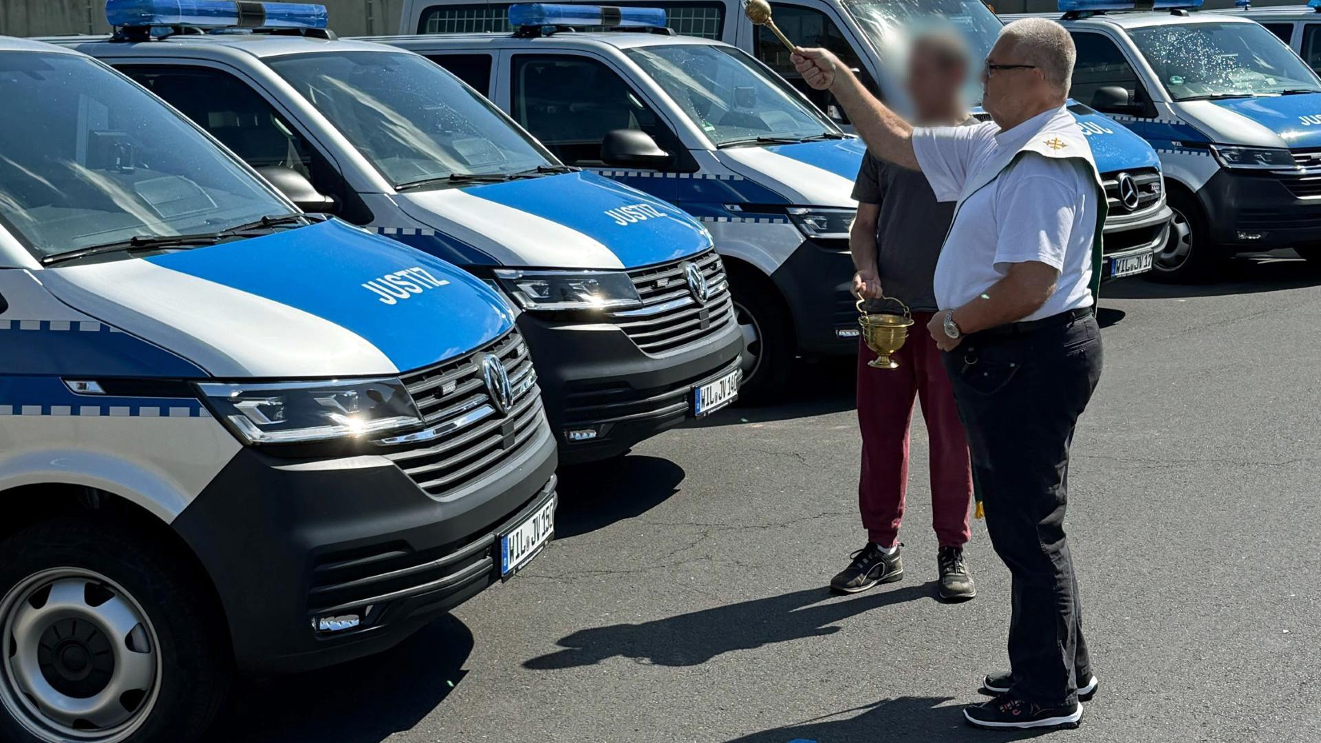 Diakon Thomas Reichert segnet die Einsatzfahrzeuge der Justizvollzugsbeamten und einen Krankentransporter